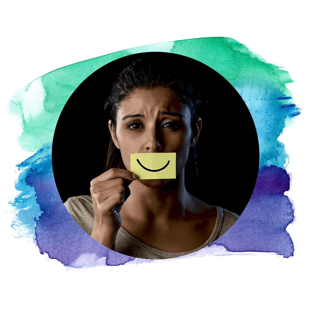 Sad woman holding post-it in front of her mouth with a smile drawn on.